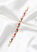 Gold bracelet with red gemstones on a white satin background