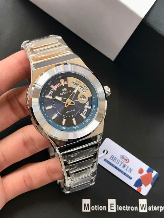 Silver wristwatch held by a hand with a visible brand tag on a dark background