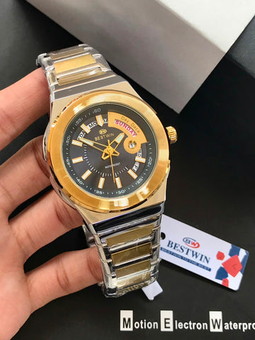 Gold and silver watch held by a hand with a visible brand tag on a dark surface.