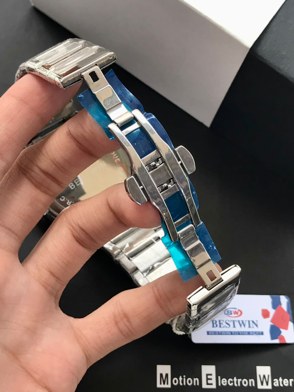 Metallic watch strap held by a hand with a blurred background