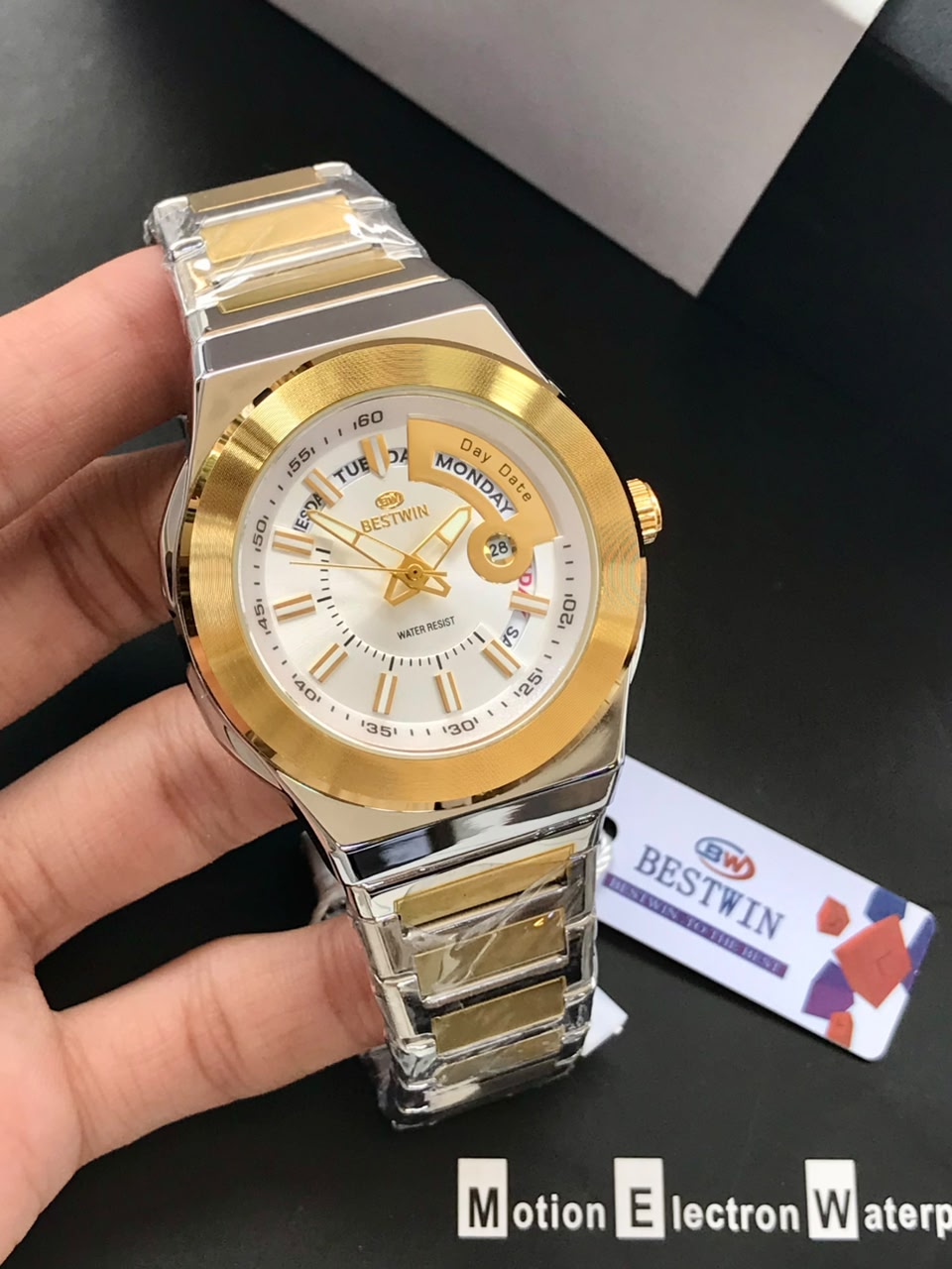 Gold and silver watch held by a hand with a dark background