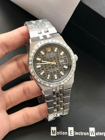 Silver watch with a detailed face held by a hand on a dark background