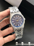 Silver watch with a blue face held by a hand on a dark background