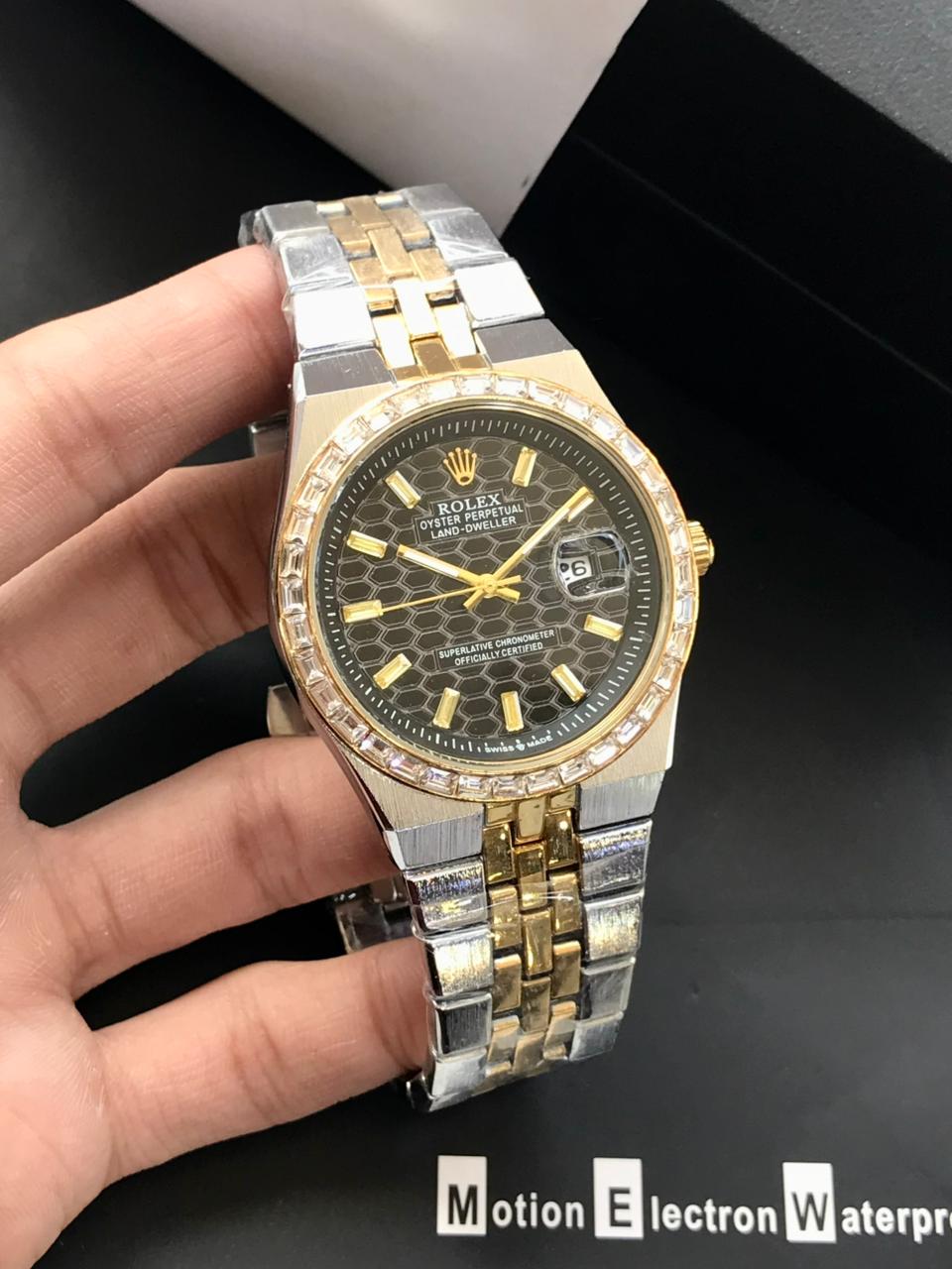 Gold and silver watch with a dark face held in a hand against a black background