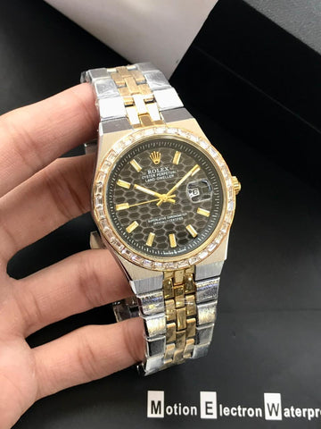 Gold and silver watch with a dark face held in a hand against a black background