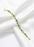 Gold bracelet with green gemstones on a white background