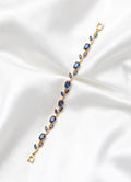 Gold bracelet with blue stones on a white satin background