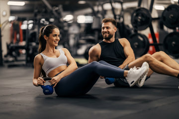 Two people exercising with kettlebells in a gym setting